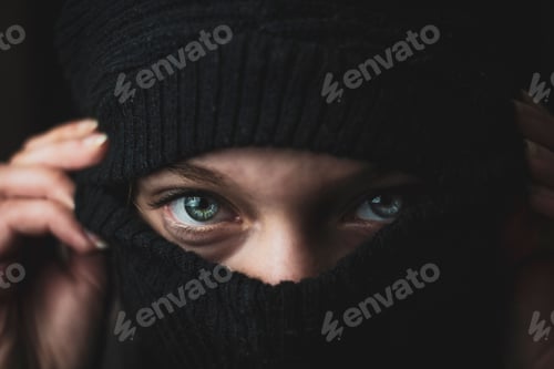 Preview: Closeup of a beautiful girl with blue eyes hiding her face under a black mask