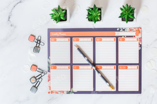 Preview: Flat lay of weekly planner on white marble desk