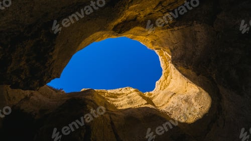 Preview: Low-angle view of an opening between the rocks with the blue sky visible from it