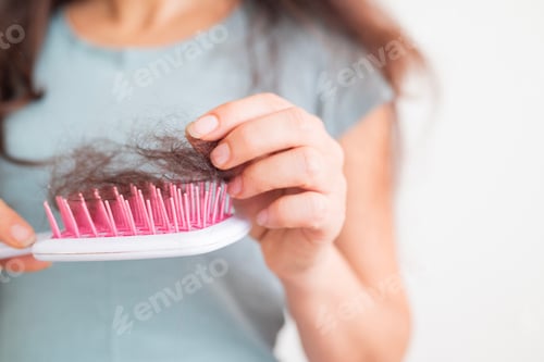 Preview: A girl holds dry, fallen hair with a comb after combing. The problem of hair loss and breakage