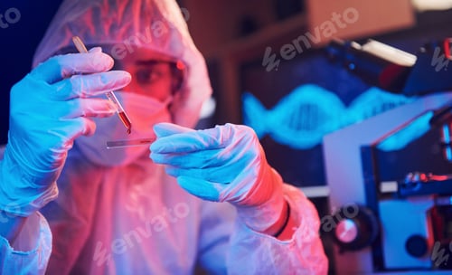 Preview: Nurse in mask and white uniform, holding tube with liquid and sitting in neon lighted laboratory