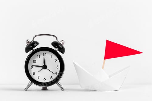 Preview: Paper boat with vintage black alarm clock on a white bakground