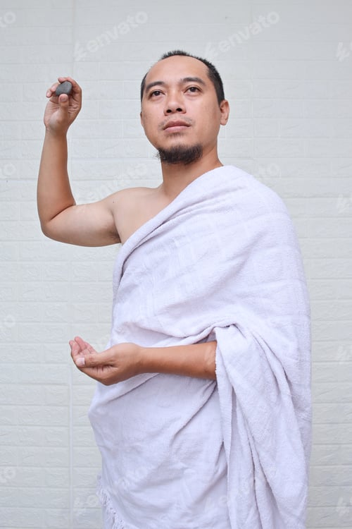 Preview: Asian muslim man performing the Jamarat ritual (stoning the devil) during Hajj season