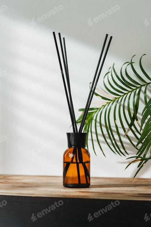 Preview: Aromatic Reed Diffuser on Wooden Table With Vibrant Green Leaves Against White Background