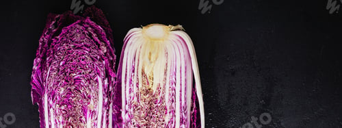 Preview: Fresh raw purple Chinese cabbage cut in half on a black concrete old background. Top view.