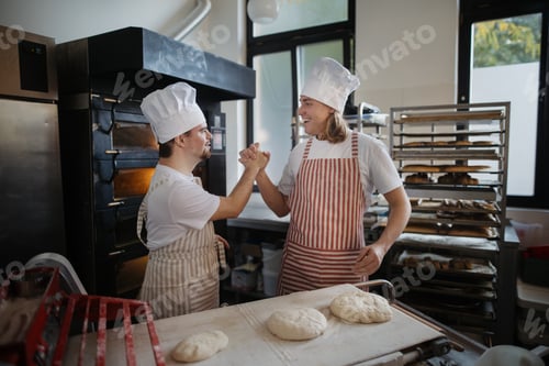 Preview: Man with down syndrom helping prepair bread in bakery with his colleague. Concept of integration