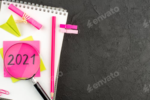 Preview: top view pink pencil written on sticky note on spiral notepad gem clips on dark background free