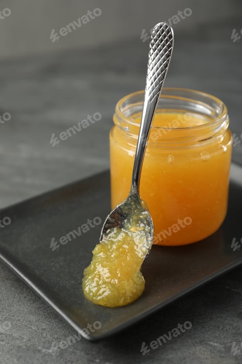 Preview: Delicious orange marmalade in jar and spoon on grey table