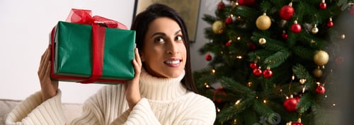 Preview: Woman Holding Christmas Gift in Decorated Home
