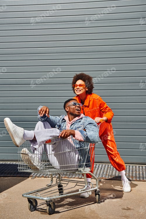 Preview: Young and excited african american best friends in sunglasses and bright outfits having fun