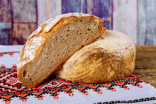 Preview: Ukrainian embroidery on freshly baked sliced bread on rustic wooden table