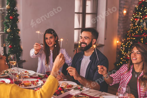 Preview: Friends waving with sparklers over Christmas dinner