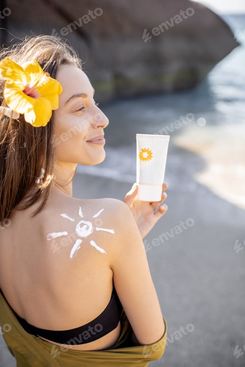 Preview: Woman with sunscreen lotion on the beach