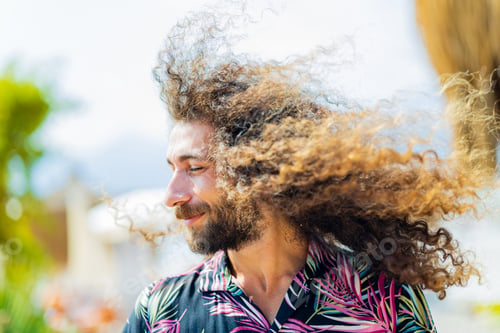 Preview: mixed race man with curly long hair outdoors ar sunny day