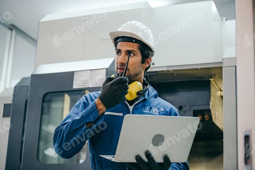 Preview: Male engineer using laptop checking on machine in the factory