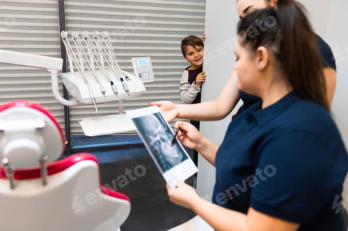 Preview: Teenager is hiding peeking out of the wall as dentists look at his x-ray