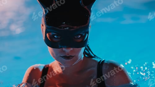 Preview: Sexy woman in bunny latex mask swimming in pool at night. Attractive chick in black swimsuit