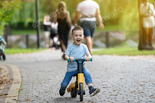 Preview: A cute happy caucasian toddler boy of three or four years old rides a bicycle or balance bike