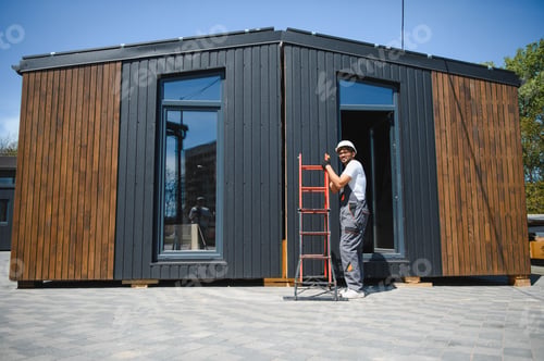 Preview: Construction worker moving modular house with ladder