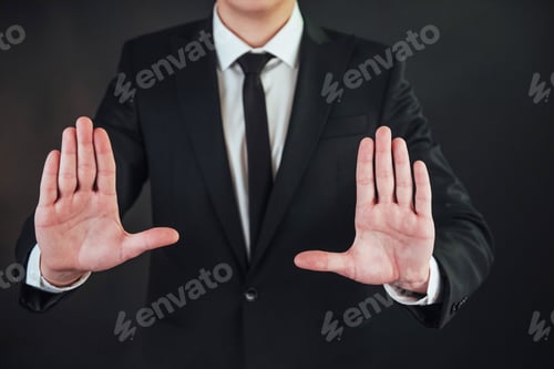 Preview: The young businessman in a suit shows his hand on a dark background isolated