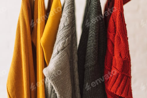Preview: Multi-colored sweatshirts hang on wooden hangers