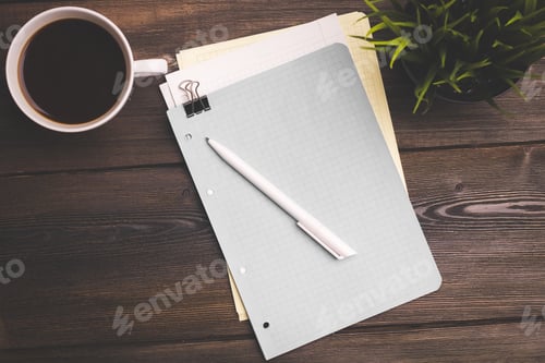 Preview: woman writes something on a sheet of paper at a wooden table coffee cup flower in a pot