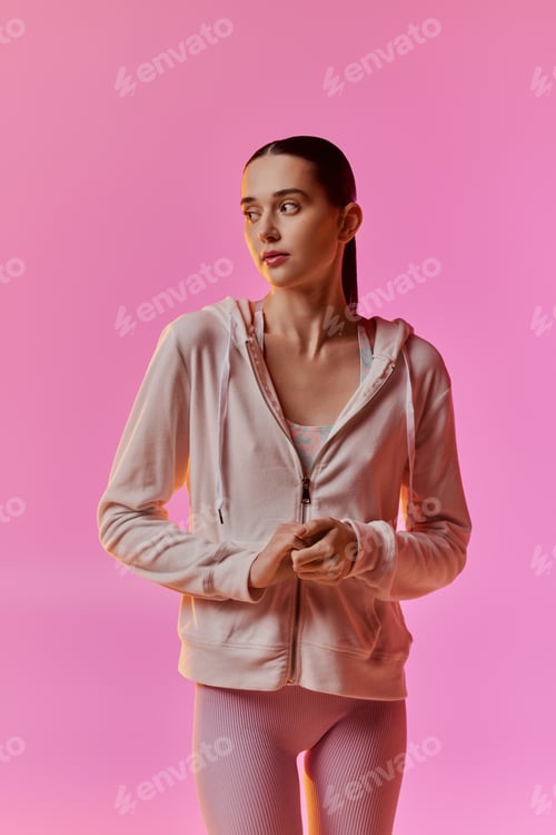 Preview: Young woman models stylish activewear against a vibrant pink background showcasing modern fashion