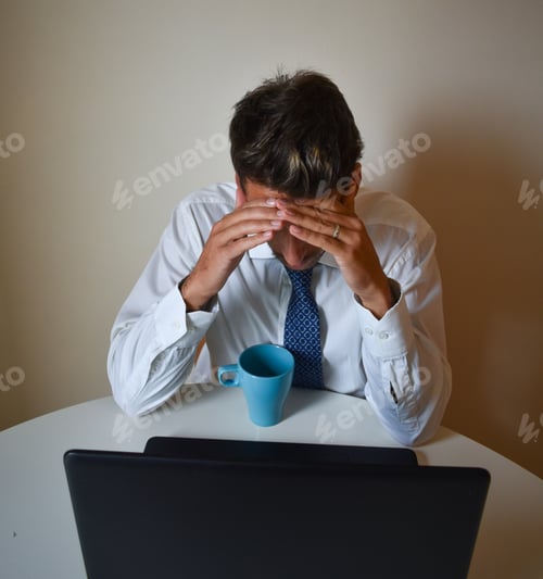 Preview: Shallow focus of a tired Caucabusinessman strained from work, sitting in front of his laptop