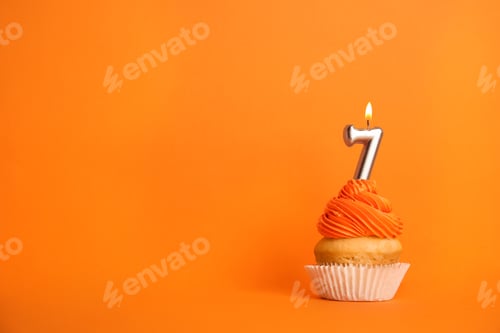 Preview: Birthday cupcake with number seven candle on orange background, space for text
