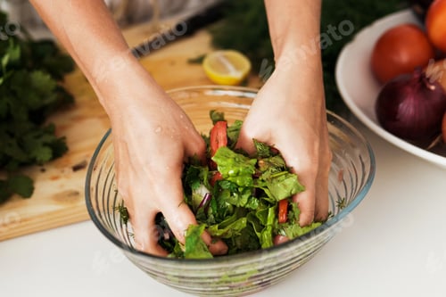 Preview: Female hands mixing vegetarian salad in the bowl