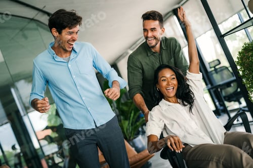 Preview: Happy multiracial team, business people having fun riding on chairs in office room