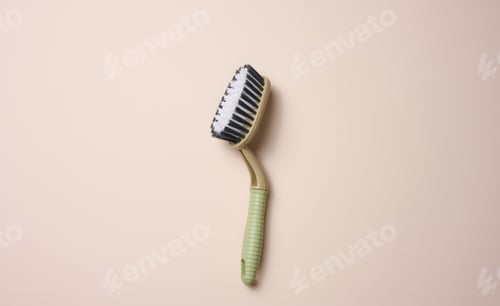Preview: Plastic brush with handle for cleaning the house on beige background, top view