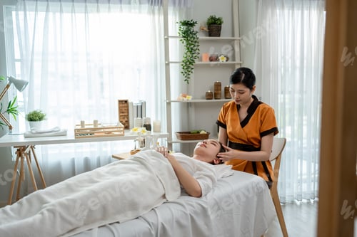 Preview: Asian young woman getting facial massage with gua sha at beauty spa.