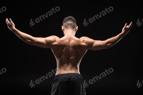 Preview: back view of shirtless muscular man standing with open arms isolated on black