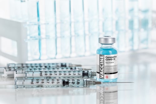 Preview: Coronavirus COVID-19 Vaccine Vial and Several Syringes On Reflective Surface Near Test Tubes
