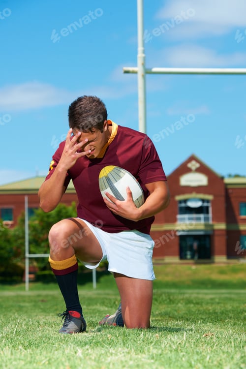 Preview: Its a mans sport. Full length shot of a young rugby kneeling on the ground while covering his eyes.