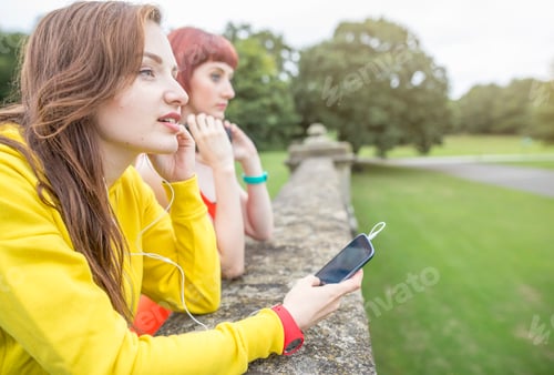 Preview: Young woman with smartphone leaning against stone wall