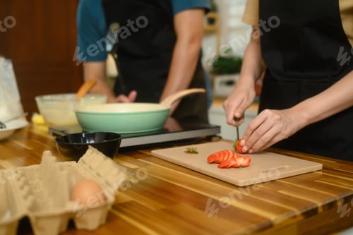 Preview: Happy young couple preparing ingredients for breakfast at home