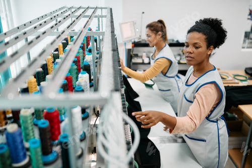 Preview: African American seamstress working at embroidery machine in a textile factory.