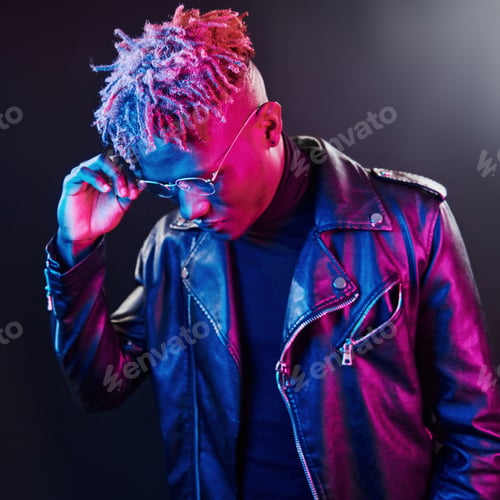 Preview: Futuristic neon lighting. Young african american man in glasses standing in studio
