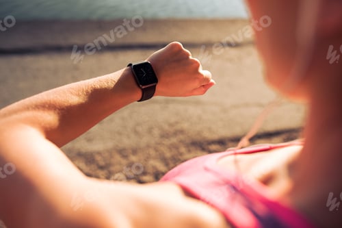 Preview: Fitness woman checking time on smartwatch