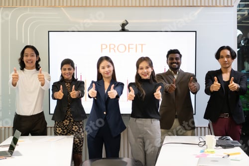 Preview: A group of multiracial businesspeople gives the thumbs up in front of the meeting room,