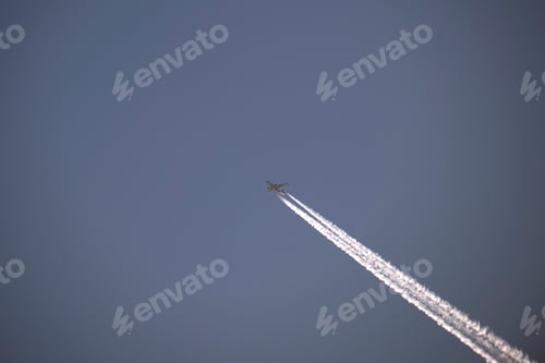 Preview: Distant passenger jet plane flying on high altitude on clear blue sky leaving white smoke