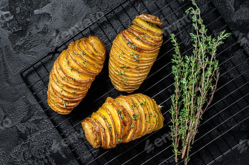 Preview: American traditional Homemade Hasselback Potato with Fresh Herbs. Black background. Top view