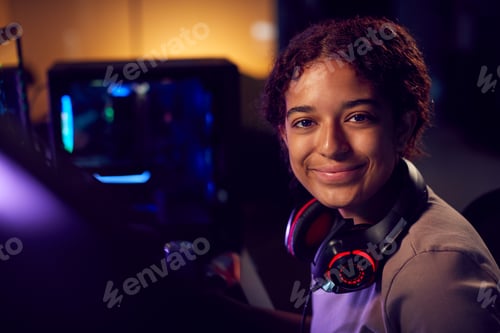 Preview: Portrait Of Teenage Girl With Headset Gaming At Home Using Dual Computer Screens