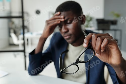 Preview: Hand of young pensive analyst in formalwear holding eyeglasses
