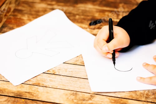 Preview: April Fool's Day concept. Child drawing papers with April Fool's Day dolls.