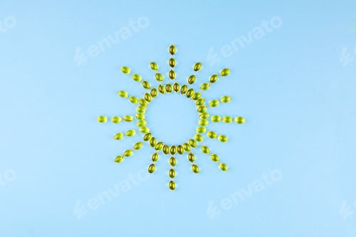 Preview: Yellow capsules with Vitamin D3 in the form of the sun with rays.
