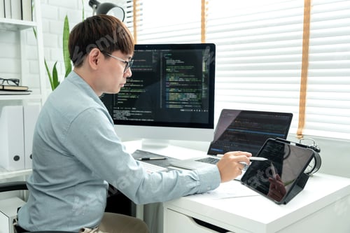 Preview: Male programmer is working to checking program code and debugging on tablet while programing