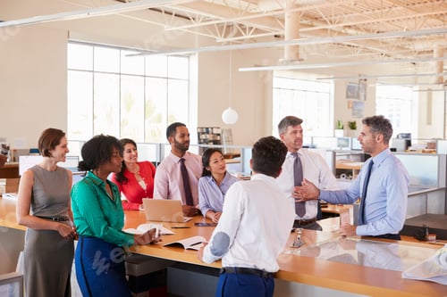 Preview: Businessman addressing team at a meeting in open plan office